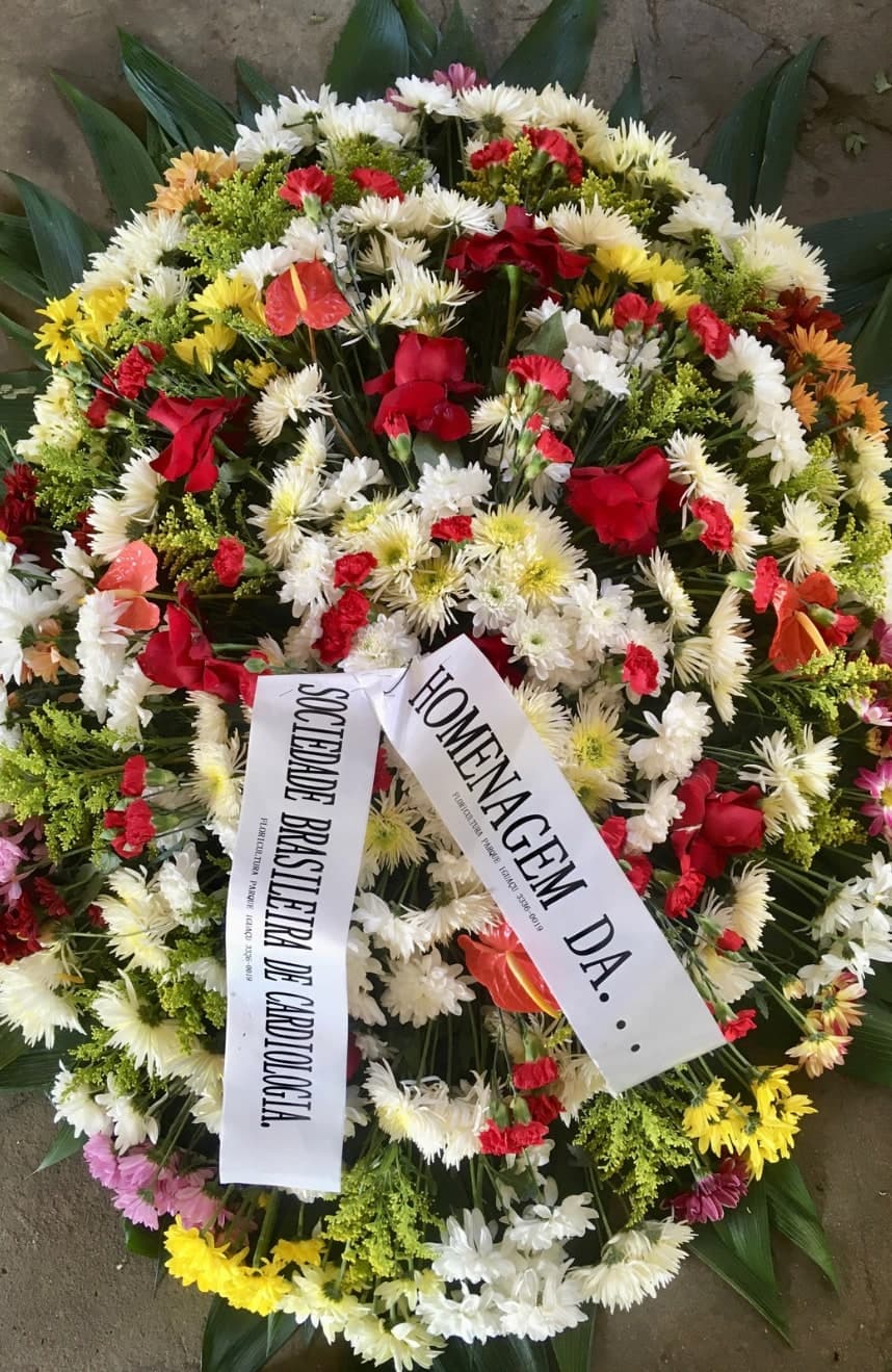Coroa nº 07: flores coloridas em vermelho, branco e amarelo e faixa de homenagem