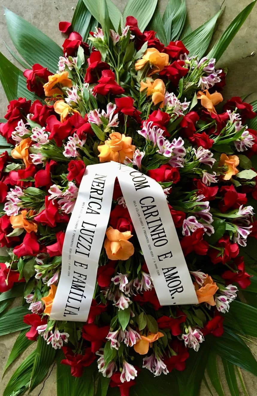 Coroa nº 11: flores vermelhas, laranja e lilás e faixa de homenagem