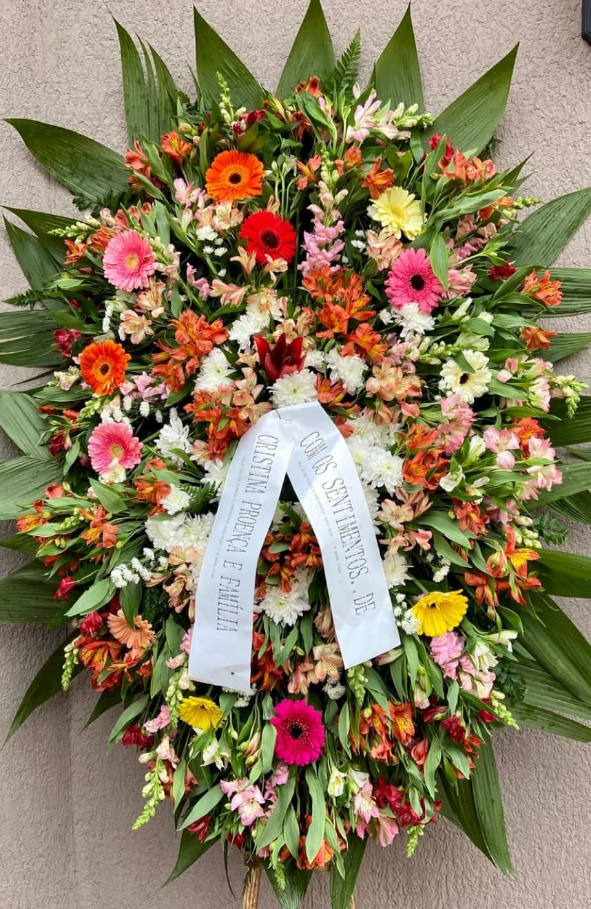 Coroa nº 12: flores coloridas em laranja, rosa e amarelo e faixa de homenagem